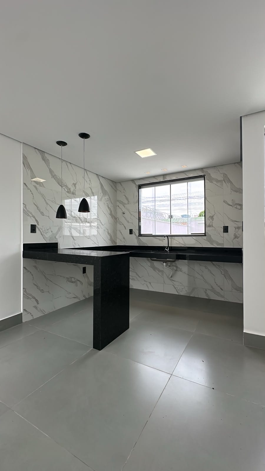Cozinha com bancada em granito preto e revestimento tipo mármore