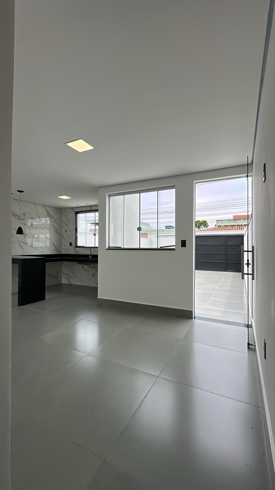 Sala conjugada com cozinha aberta e saída para a garagem